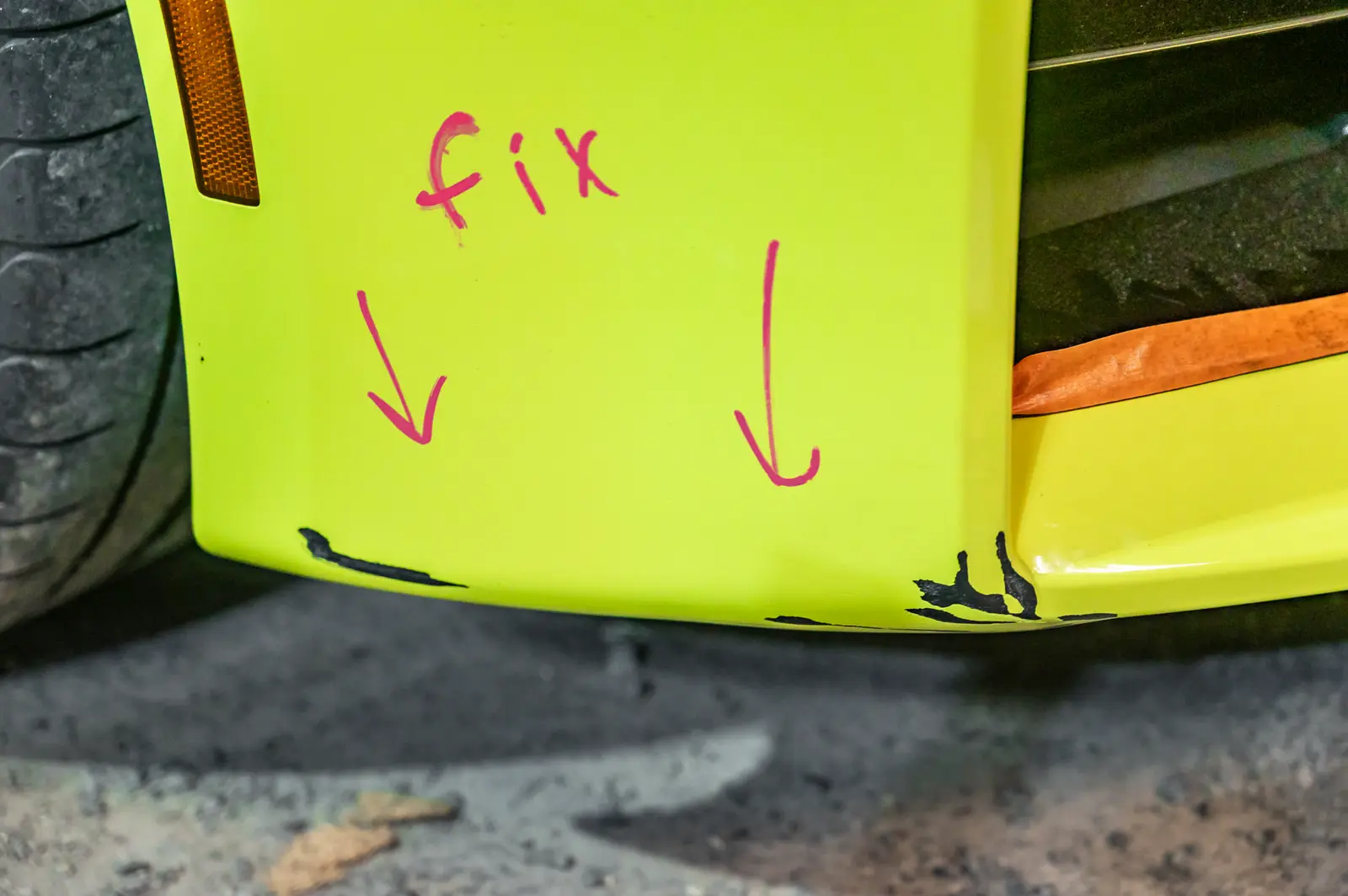 Damage on a yellow BMW bumper, marked for repair by the shop after an assessment