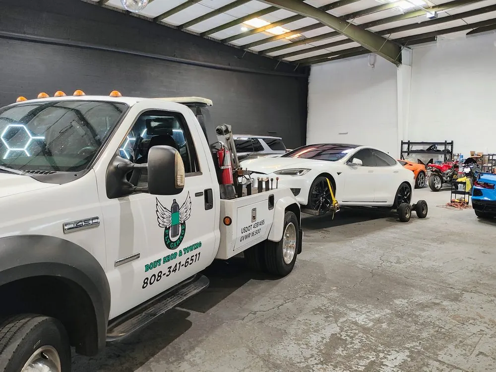 The Fly Garage tow truck in the shop with a white Tesla on wheel dollies
