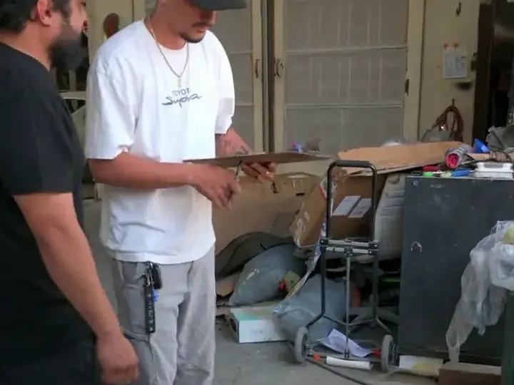 Two Fly Garage team members writing up a repair beside a car with its hood open